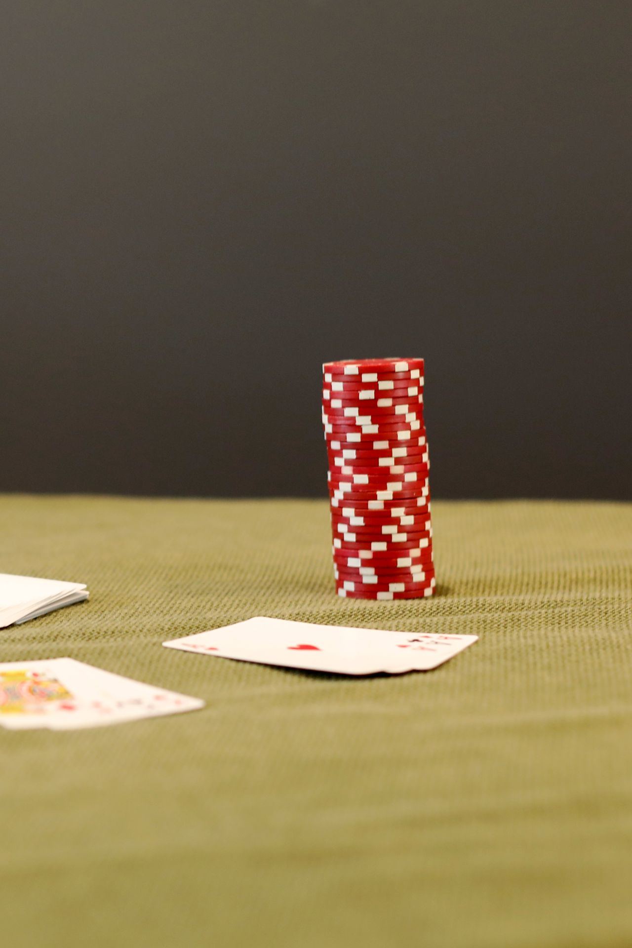 Chip poker merah putih dan kartu terbuka di atas meja hijau