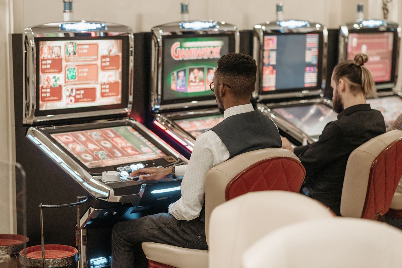 Beberapa orang bermain di mesin slot dalam ruangan kasino