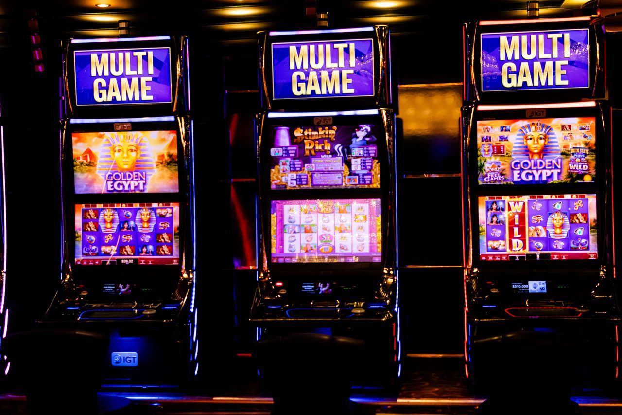 Tiga mesin slot multi permainan menyala berjajar di kasino