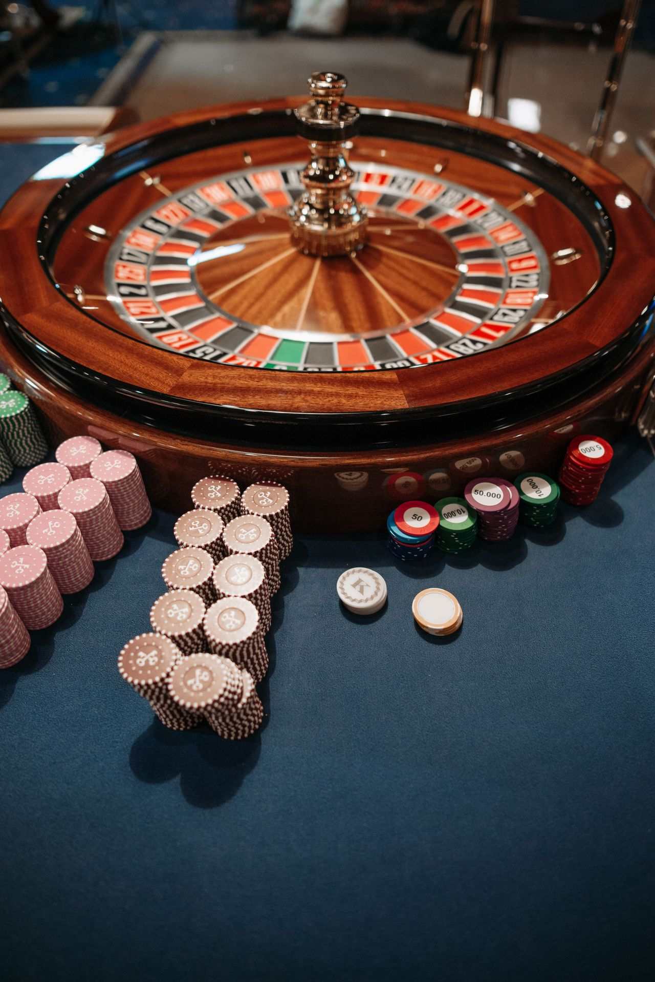 Roda roulette kayu dan tumpukan chip kasino di atas meja