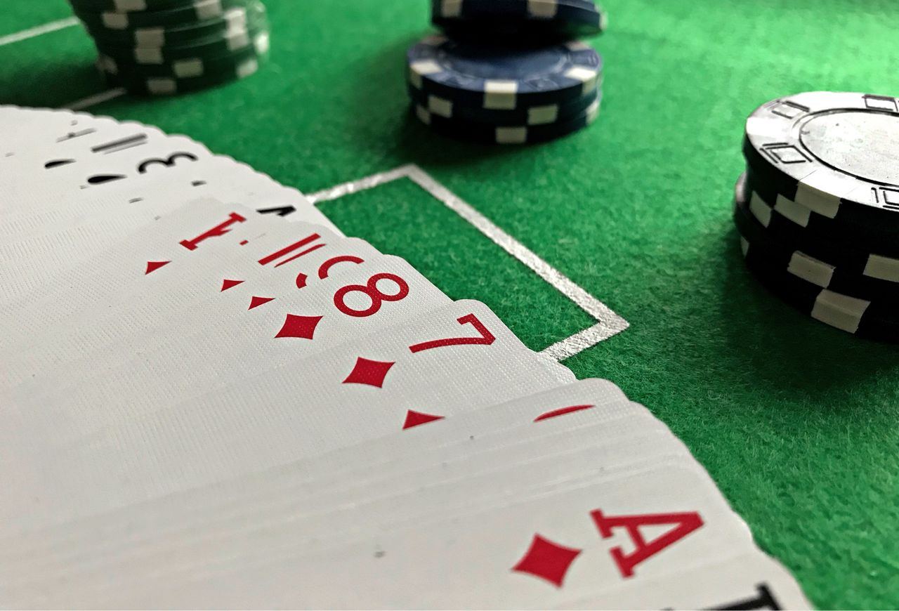 Kartu remi terbuka dan tumpukan chip poker di atas meja hijau