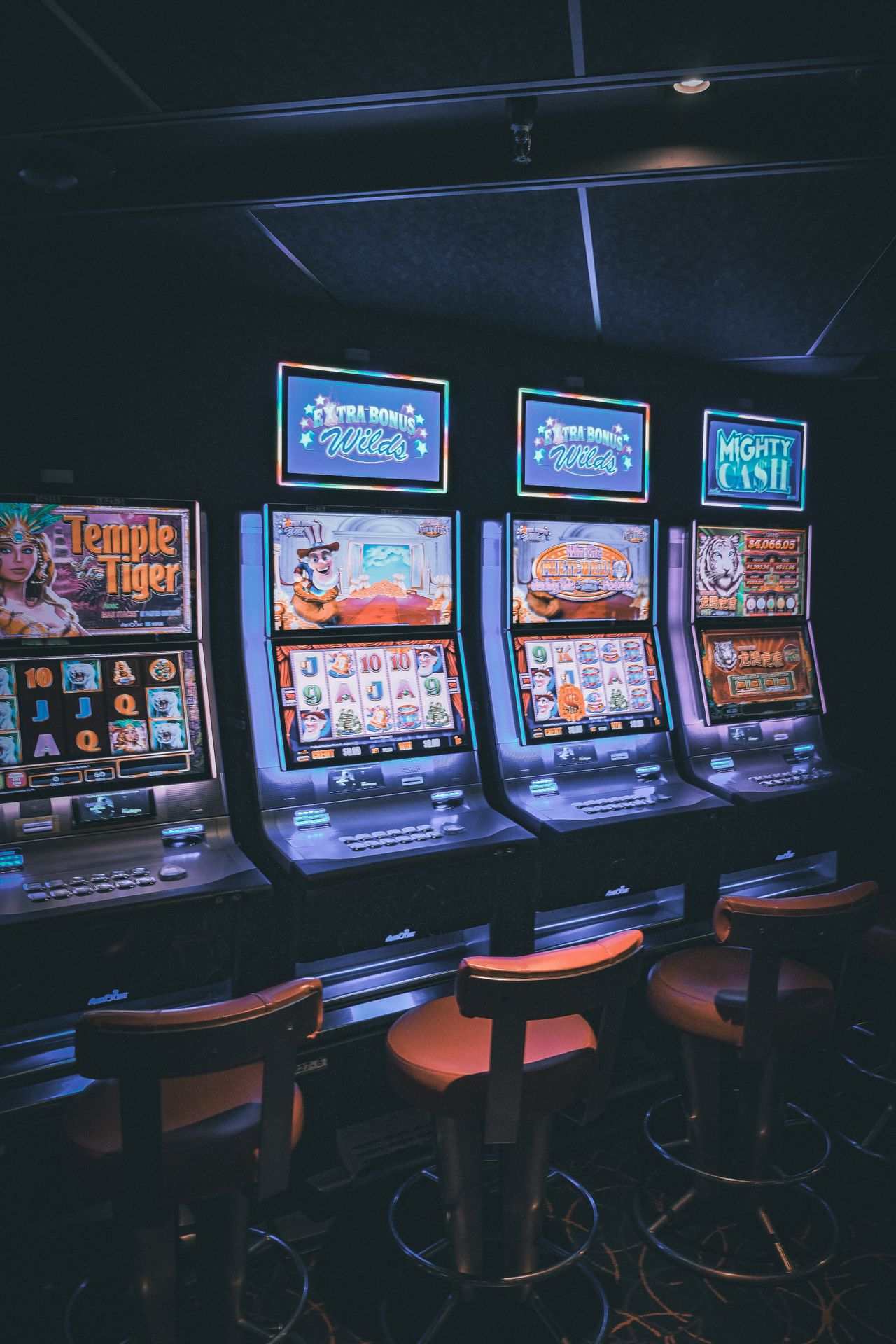 Deretan mesin slot menyala berwarna-warni di kasino yang temaram
