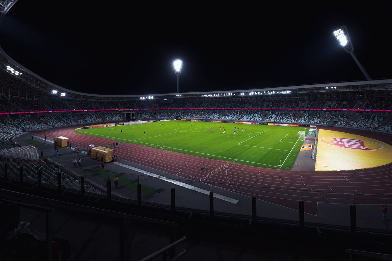Stadion sepak bola menyala di malam hari dengan lapangan hijau